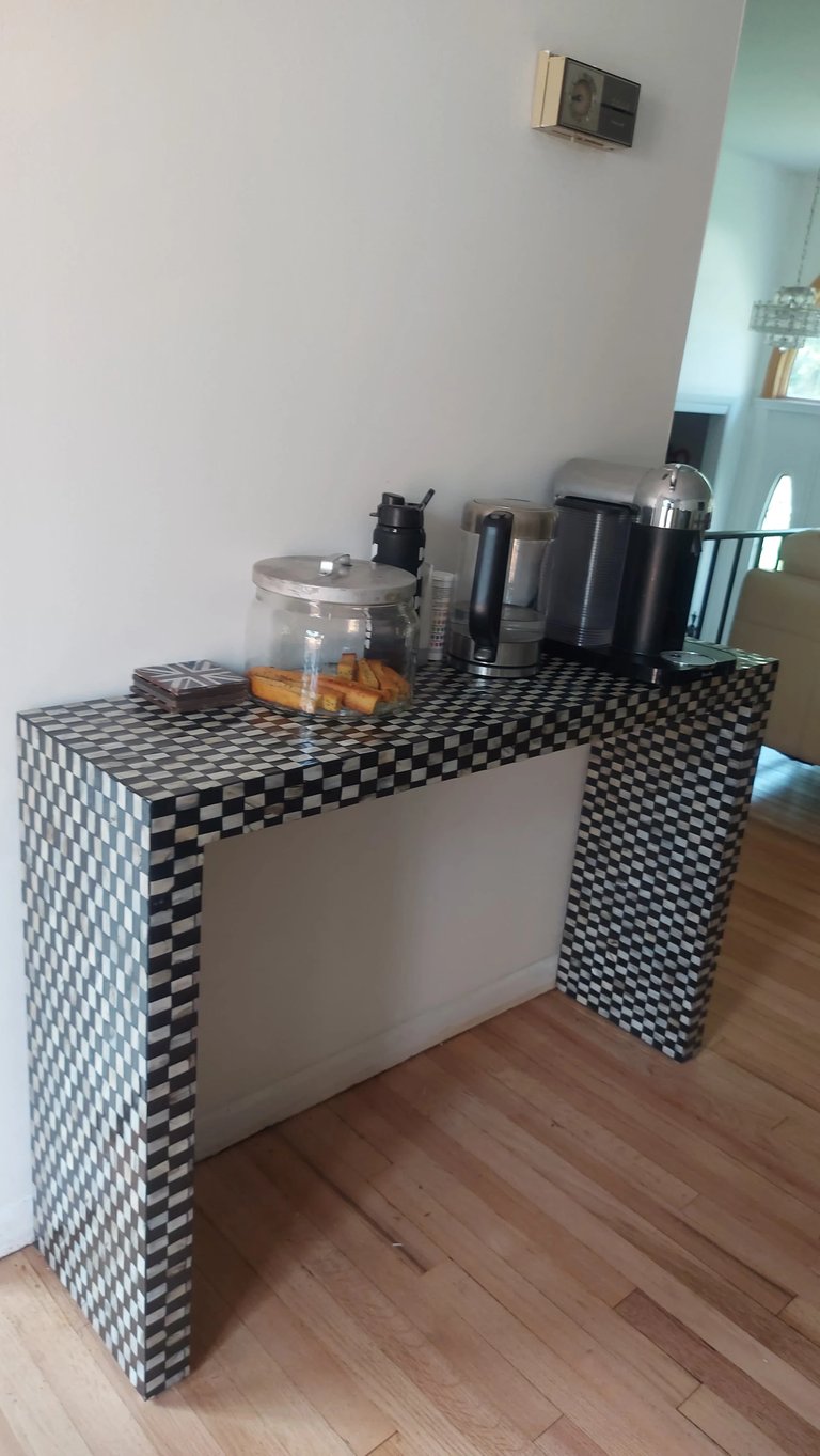 Black and white checkered desk with kitchen appliances and a glass container with food items on top